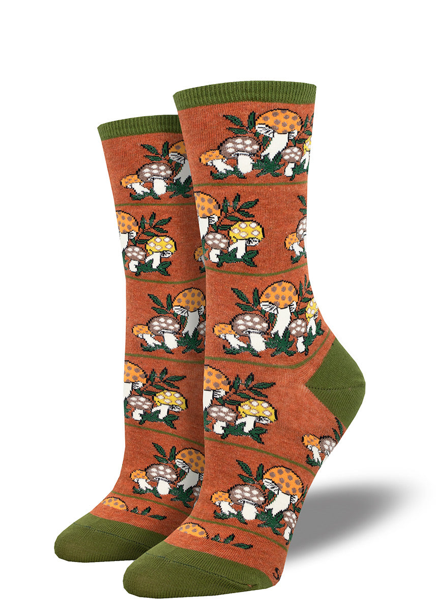 Cute spotted mushrooms in a palette of '70s-inspired colors "grow" in a repeating pattern on rust-toned women's crew socks with olive green accents at the heel, toe and cuff.