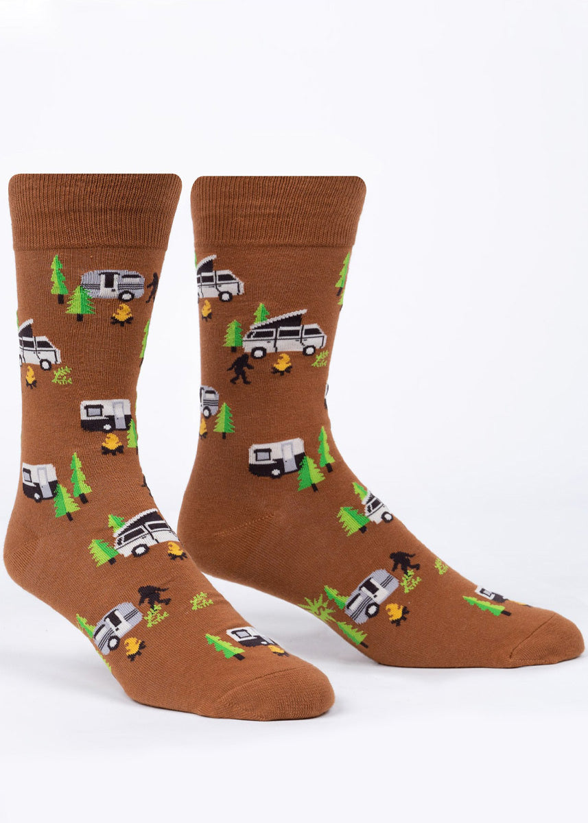 Brown novelty camping crew socks for men show camper vans in the woods with campfires and Sasquatches wandering around!