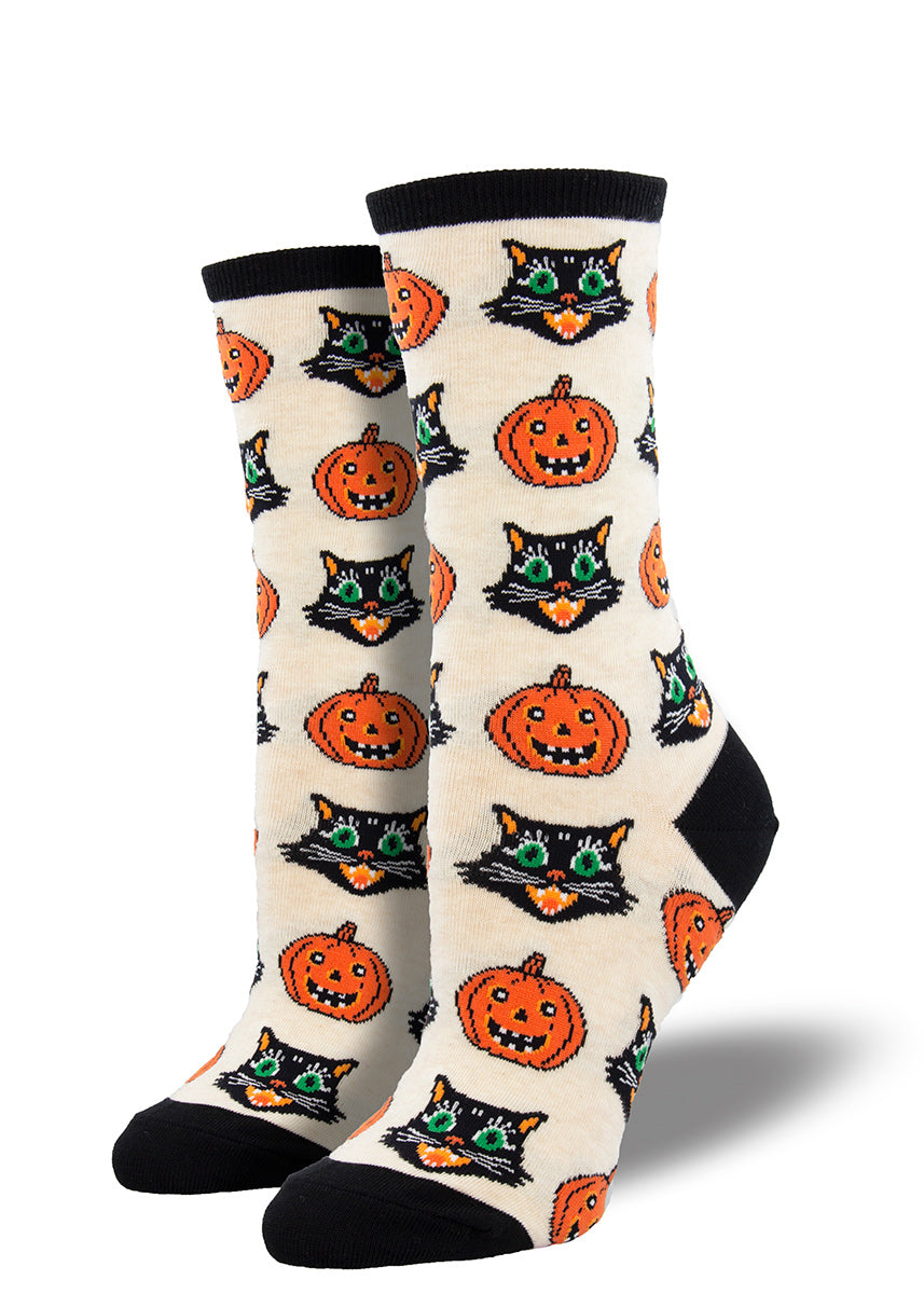 Halloween crew socks for women feature vintage-inspired black cat faces and smiling jack-o&#39;-lanterns on a cream background.