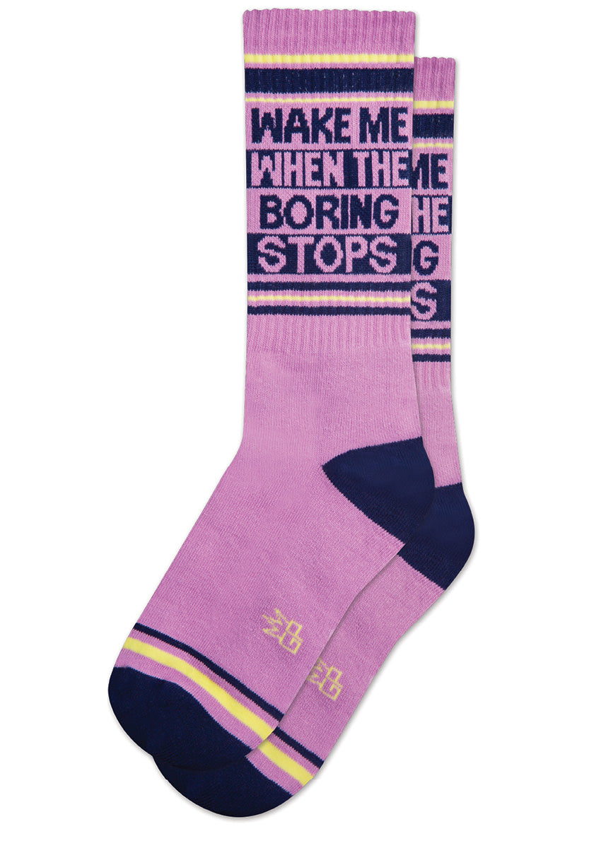 Funny retro gym socks say "Wake me when the boring stops" on a lilac background with navy stripes and accents. 