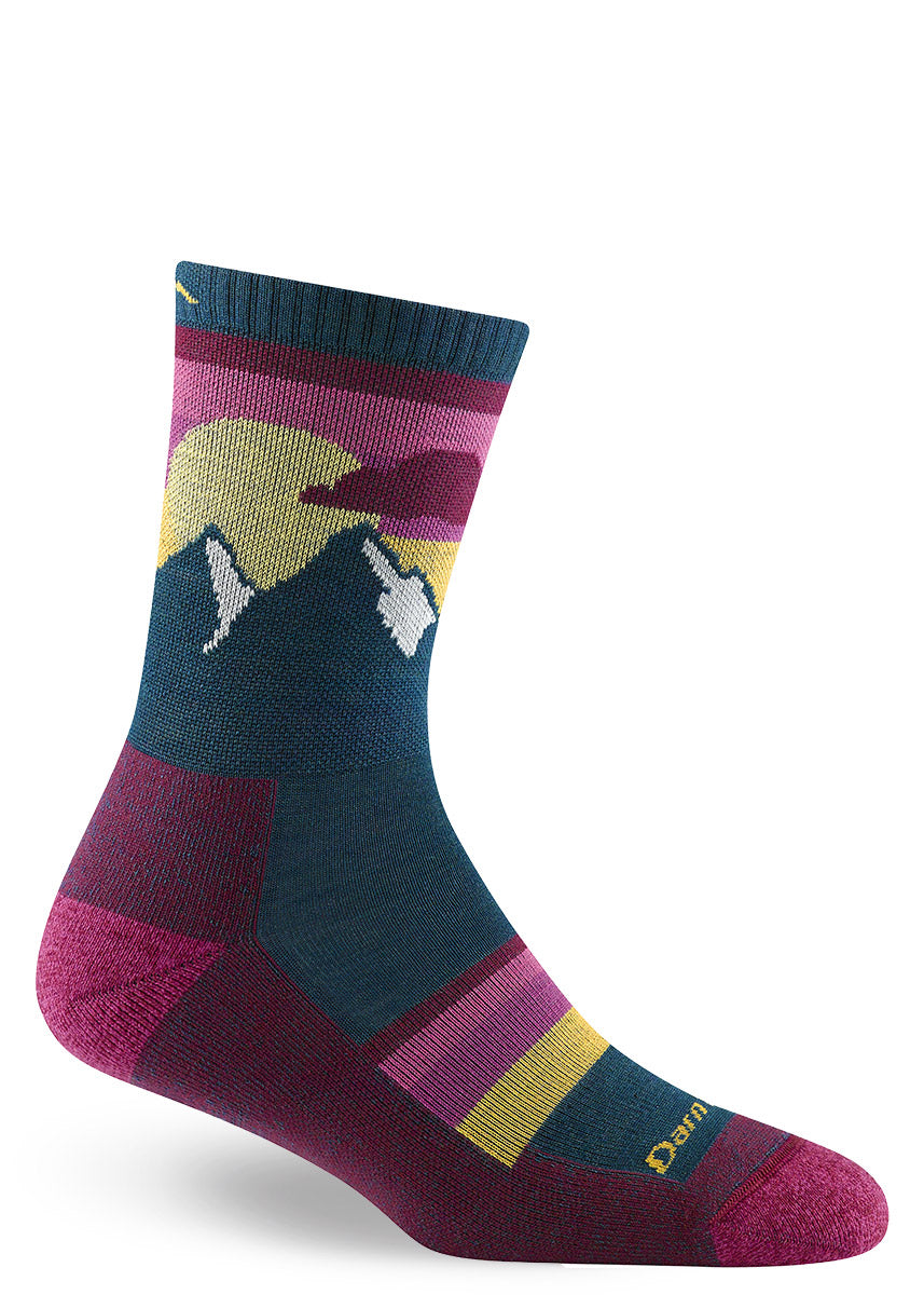 Deep teal and magenta hiking socks with snow-capped mountain peaks and a big pink sky with a yellow sun.